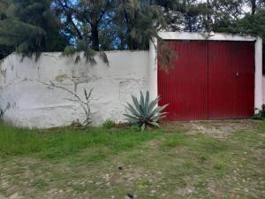 uma garagem vermelha com uma porta vermelha ao lado de uma parede em Casa de campo, cerca del aeropuerto internacional del Vacío em Guanajuato