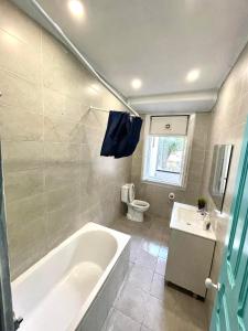 ein Badezimmer mit einer Badewanne, einem WC und einem Waschbecken in der Unterkunft Lisboa Parque Guest House in Lissabon