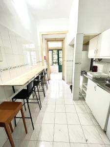 eine Küche mit weißen Schränken sowie Tischen und Stühlen in der Unterkunft Lisboa Parque Guest House in Lissabon