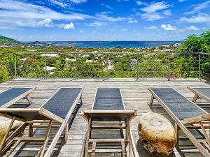 a wooden deck with tables and chairs and the ocean at Casa Del Mar, luxury and magical view of Orient Bay in Orient Bay