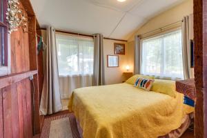 a bedroom with a bed with a yellow blanket and a window at Bayfront Red Creek Vacation Rental with Boat Dock! in Red Creek