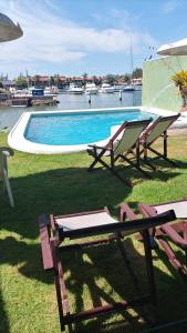 una piscina con 2 sillas de césped y una mesa en Morada do Canal Suites em Búzios, en Búzios