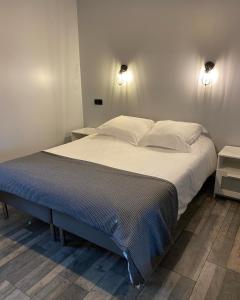 a large bed in a bedroom with two lights on the wall at Gites Le Grand Tornage in Évaux-les-Bains