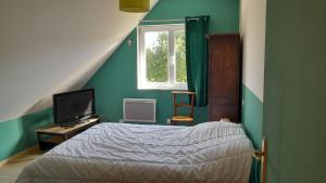 Schlafzimmer mit einem Bett, einem Fenster und einem TV in der Unterkunft Grande maison, calme, proche de la mer in Camoël