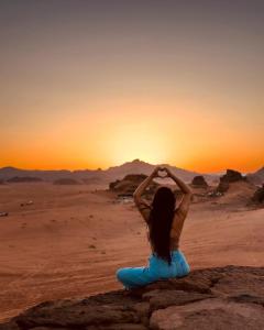 una mujer sentada en una roca en el desierto viendo la puesta de sol en Wadi Rum desert magic, en Wadi Rum