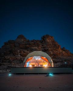 een glazen koepel met een bank 's nachts bij Wadi Rum desert magic in Wadi Rum
