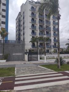un grand bâtiment blanc avec des palmiers devant lui dans l'établissement Lindo apto em frente ao mar., à Praia Grande