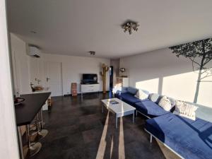 uma sala de estar com um sofá azul e uma mesa em La VILLA DES PINS Maison Standing 7 pers Terre et Mer em Brach