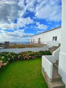 een wit gebouw met een tuin met roze bloemen bij Casa do Pisão - Cosy and Modern Two-Bedroom Townhouse in Angra do Heroísmo