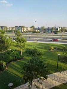 a park with green grass and trees and a street at شقه فندقية 3غرف بمدينتي امام كرافت زون01117805968 in Madinaty