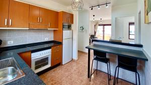 a kitchen with wooden cabinets and a counter top at Bahia Sol Dream -Caleta de Fuste- in Caleta De Fuste