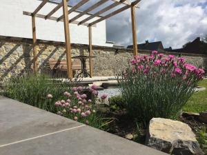a garden with pink flowers and a wooden pergola at Gite L'Abeille 