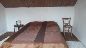 Bett in einem Zimmer mit 2 Tischen und einem Stuhl in der Unterkunft Sous les chênes – Gîte nature dans le Berry Sud in Saint-Saturnin