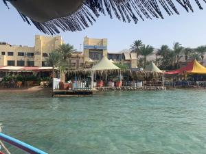 a beach with tables and umbrellas on the water at Al-Amer Hostel 2 in Aqaba