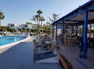 a patio with tables and chairs next to a pool at JUMA HOLIDAYS in Puerto del Carmen