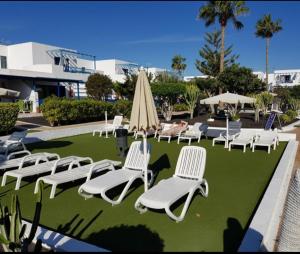 a group of chairs and umbrellas on a lawn at JUMA HOLIDAYS in Puerto del Carmen