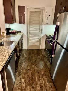 a kitchen with a stainless steel refrigerator and wooden floors at Excellent Location- Perfect Shared Homestay! in Yaphank