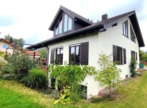 una casa bianca con finestre nere di Ferienwohnung Ruhequell a Königsfeld im Schwarzwald