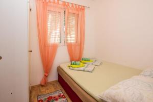 1 dormitorio con 1 cama y una ventana con cortinas de color naranja en Apartment Emina, en Batalaži