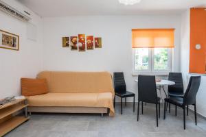 Cette chambre comprend un canapé, une table et des chaises. dans l'établissement Apartment Emina, à Batalaži