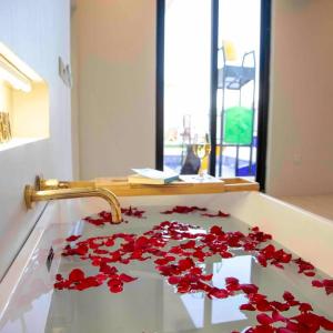 um lavatório de casa de banho com flores vermelhas num balcão em المرفأ 2 شاليه مع مسبح والعاب مائية وغرف نوم فاخرة em Khalij Salman