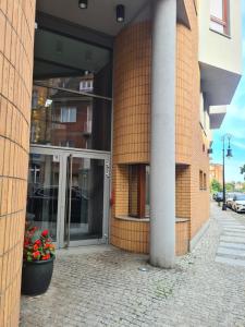 een toegang tot een gebouw met glazen deuren en bloemen bij Warta LUX Apartment, self check-in 24h, free parking in Poznań