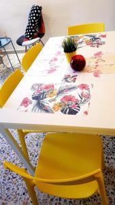 a table with a yellow chair and a white table with flowers at La Casina di Isola in Livorno