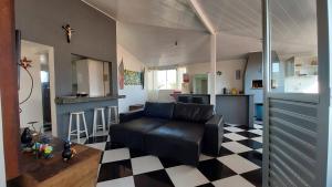 sala de estar con sofá de cuero negro y cocina en Cobertura a 200m da Praia de Ponta das Canas, en Florianópolis