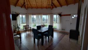 ein Esszimmer mit einem Tisch, Stühlen und Fenstern in der Unterkunft Las Condalias in Puerto Madryn