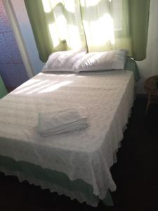 Lua de Aquarius Boutique Hostel في Tamoios: سرير عليه شراشف بيضاء ومناشف