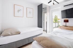 two beds in a white bedroom with a tv at VI&LA - Apart House in Piešťany