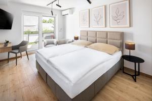 a bedroom with a large white bed and a desk at VILA Apartments Piešťany Family Terrace in Piešťany