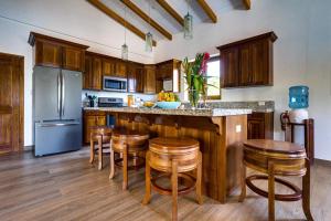 a kitchen with wooden cabinets and a island with bar stools at South Gull Villa - Brand New Ocean Front in Riversdale