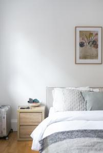 a white bedroom with a bed and a night stand at Generously large 1 bedroom apartment in Farringdon in London