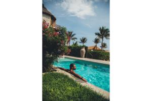 a man laying in a swimming pool at a resort at Casa Joseph Zicatela - Adults Only in Puerto Escondido