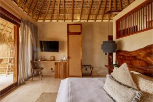 a bedroom with a bed and a desk and a television at Casa Joseph Zicatela - Adults Only in Puerto Escondido