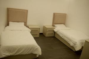 twee bedden in een kamer met twee nachtkastjes bij Gloria Chalet in Al Rama