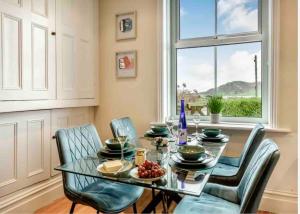 a dining room with a glass table and chairs and a window at Jack's House in Tywyn