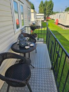 eine Terrasse mit 2 Stühlen und einem Tisch auf der Veranda in der Unterkunft Liberty Caravan Hire in Chapel Saint Leonards