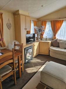 a living room with a television and a fireplace at Liberty Caravan Hire in Chapel Saint Leonards