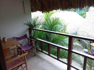 a balcony with a table and chairs and palm trees at El Leon Feliz Palomino in Palomino