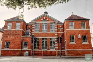 een rood bakstenen gebouw op de hoek van een straat bij Sleep Hotel in Worthing