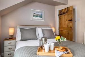 a bed with a tray of food and flowers on it at Seagrass Cottage - Aberdovey in Aberdyfi