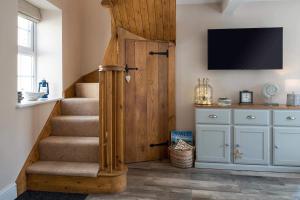 uma escada com uma porta e uma televisão na parede em Seagrass Cottage - Aberdovey em Aberdyfi