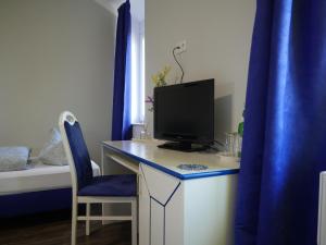einen Schreibtisch mit einem Computer mit einem blauen Vorhang in der Unterkunft Hotel & Ristorante Positano in Radeburg