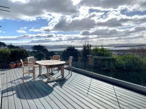 a wooden deck with a table and chairs on a balcony at Bodwennol - A Stunning House! in Aberdyfi