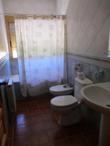 uma casa de banho com um WC branco e um lavatório. em Apartamentos Rurales El Tormagal 