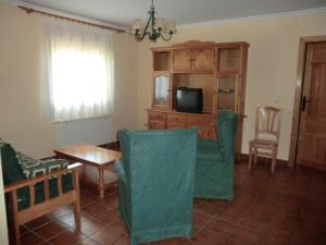 un salon avec des fauteuils verts et une télévision dans l'établissement Apartamentos Rurales El Tormagal, 