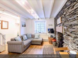a living room with a couch and a stone wall at Pebble Cottage in Aberdyfi