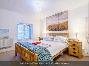 Un dormitorio con una cama grande y una mesa con una lámpara. en Pebble Cottage en Aberdyfi